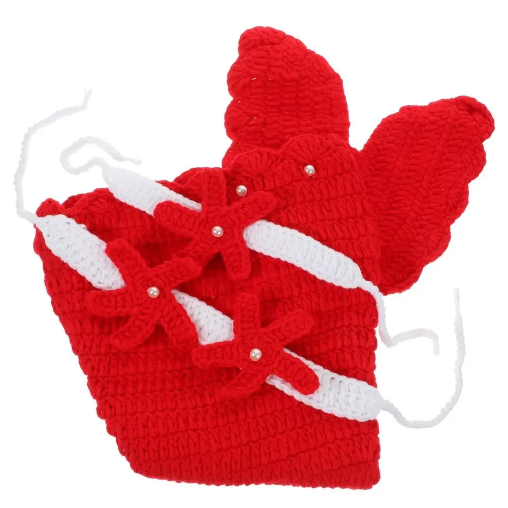 Folded red knitted mermaid tail with its fin and starfish accessories shown close up