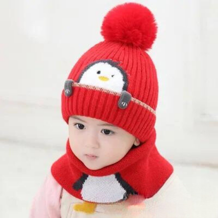 Child wearing a red penguin pom-pom hat and matching scarf against a light background
