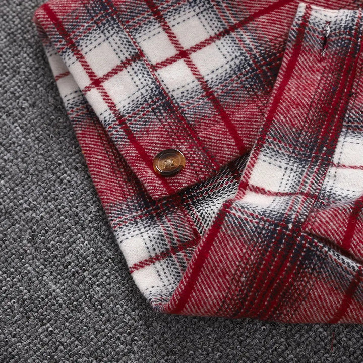 Close-up of red, white and dark plaid jacket fabric with a brown button and stitched edge