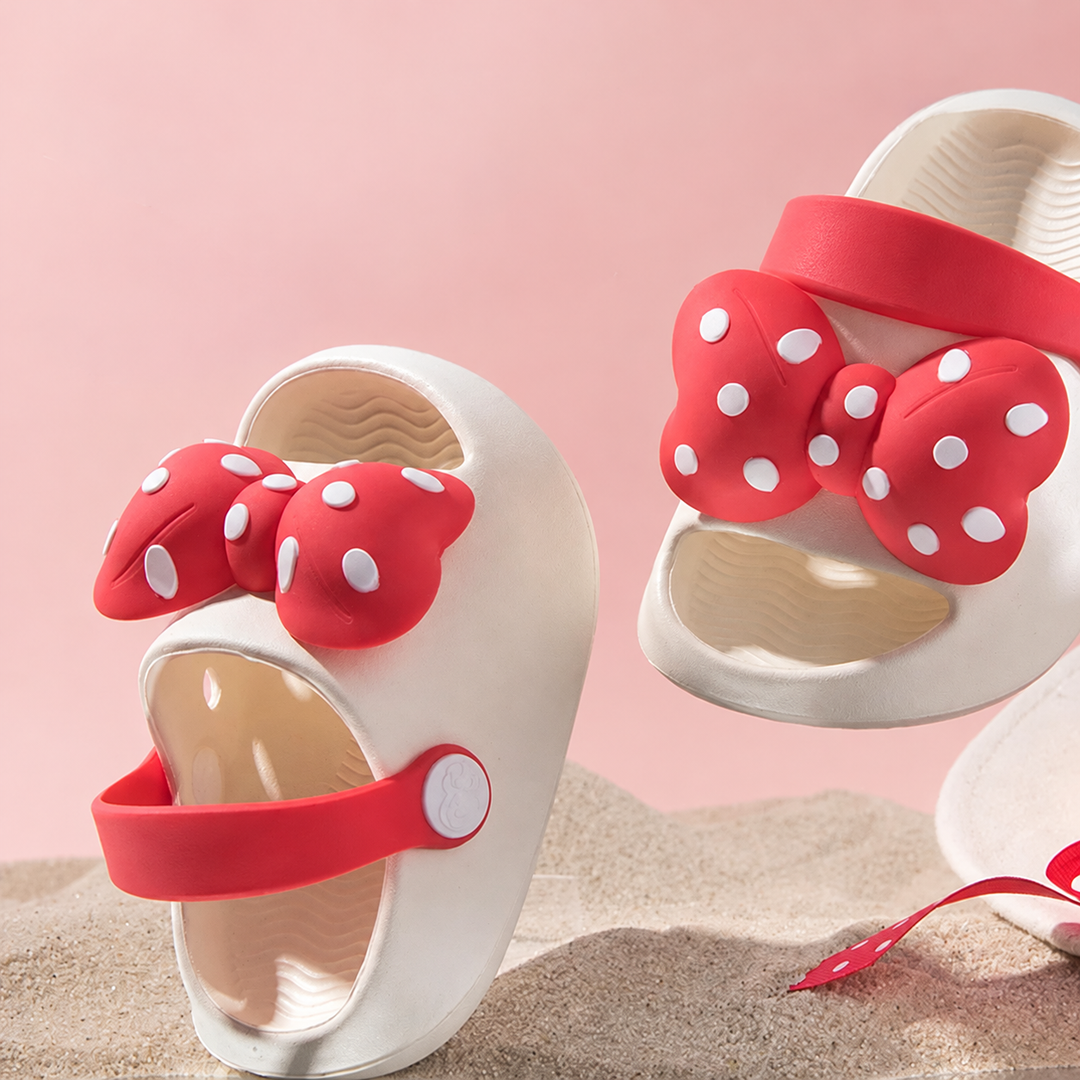 Close-up of white open-toe sandals with large red polka-dot bows and red straps