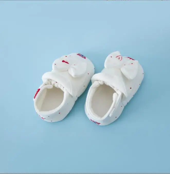 White baby shoes with bow fronts, red details and white lining
