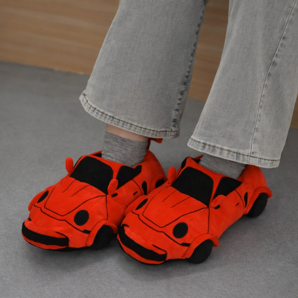 Red plush racing car slippers worn with gray pants indoors