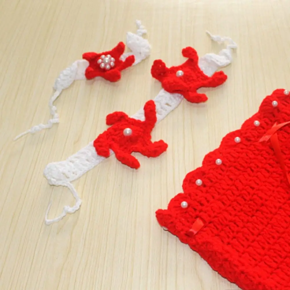 Close-up of red starfish decorations on white knitted bands beside a red mermaid tail
