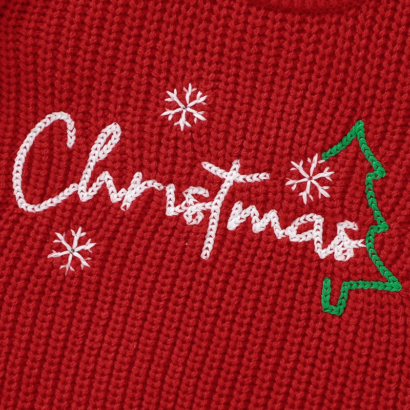 White Christmas lettering, snowflakes, and a green tree embroidered on the red knit sweater.