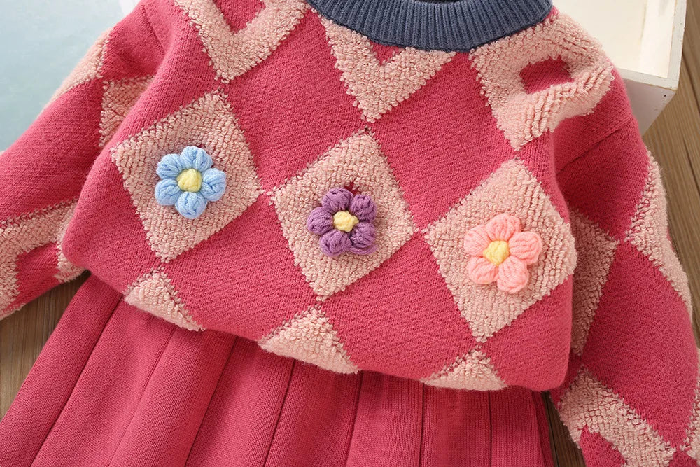 Close-up of raised blue, purple and pink flowers on the red diamond-knit sweater
