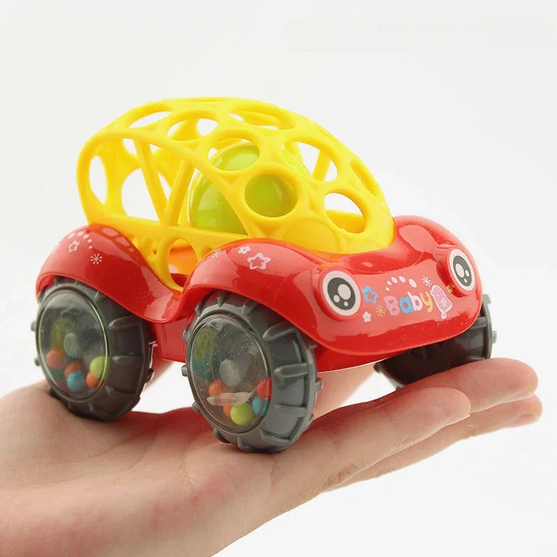Red rattle toy car with a yellow lattice top and bead-filled wheels resting on a hand