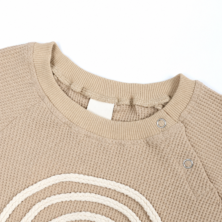 Ribbed neckline and shoulder snaps on a beige rainbow baby bodysuit