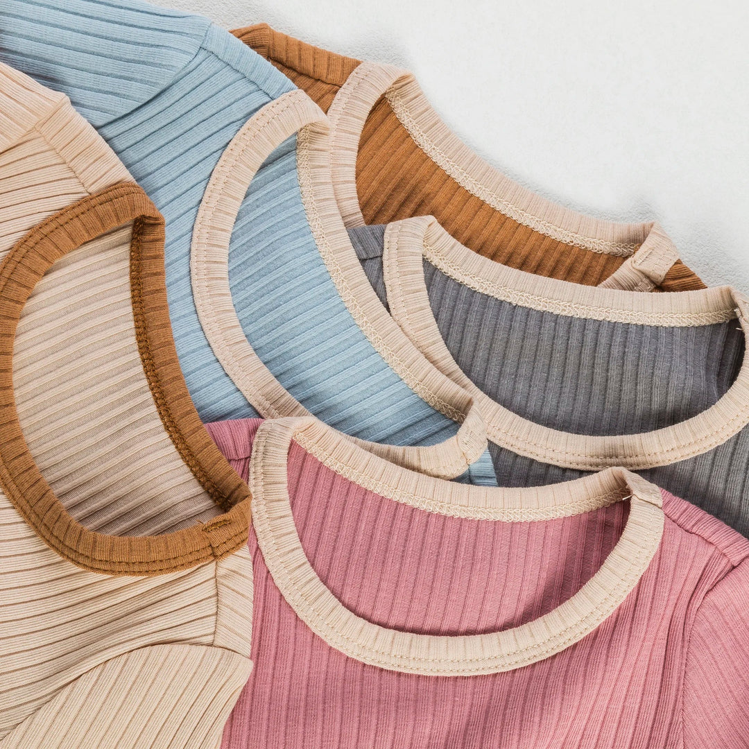 Close-up of round necklines and ribbed fabric on colorful cotton baby rompers