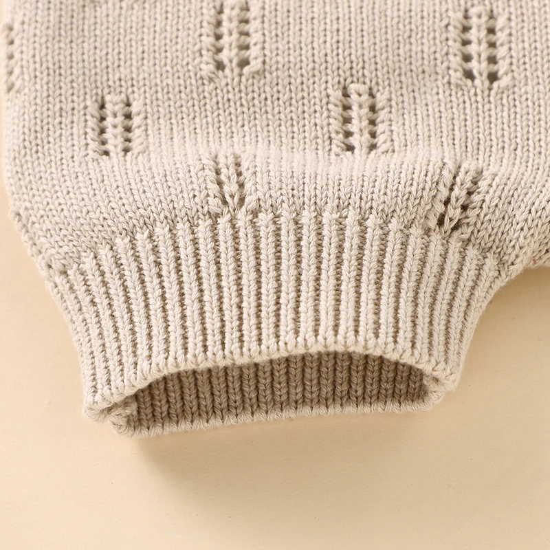 Close-up of an elastic ribbed leg cuff and textured knit on beige baby overalls.