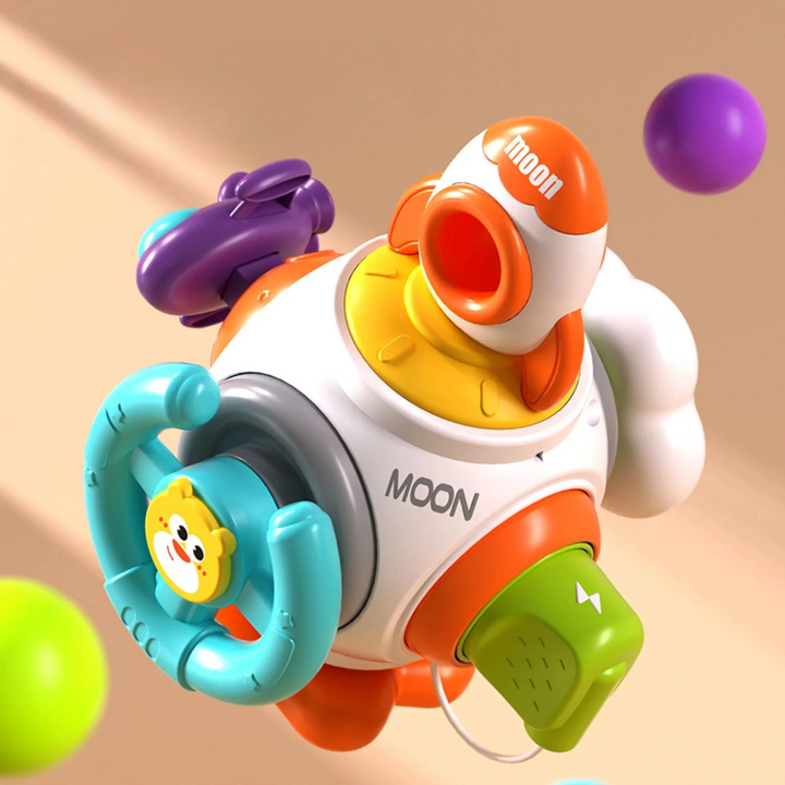 Rocket activity toy with a teal steering wheel, orange rocket, purple spaceship, and green pretend plug
