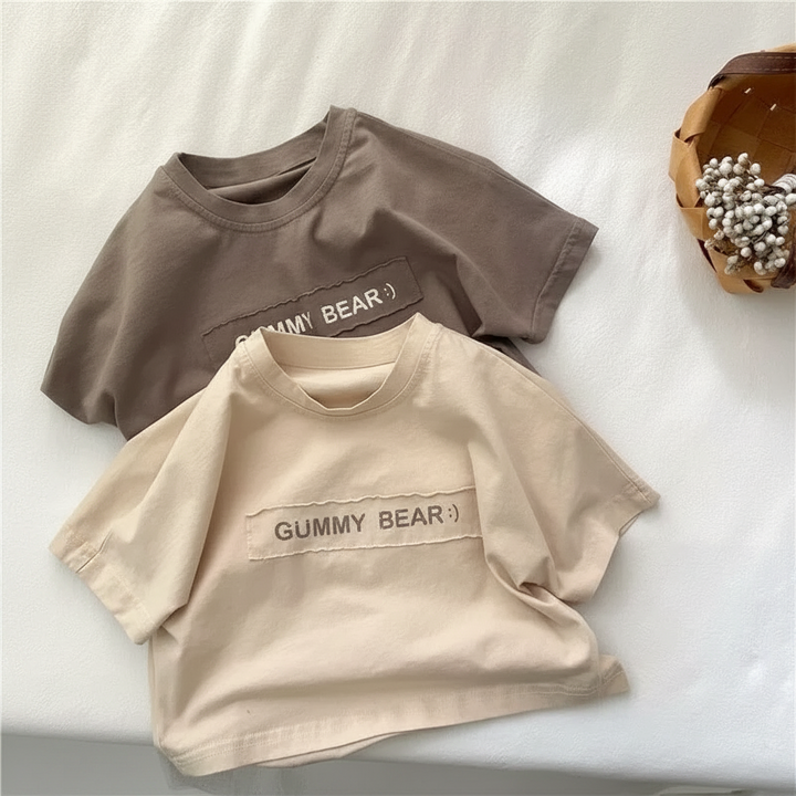 Brown and beige short-sleeve T-shirts with round necklines arranged on white bedding