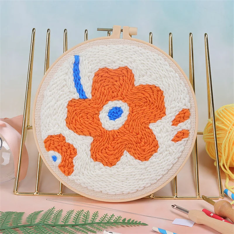 Round embroidery hoop with a textured orange flower and blue details.