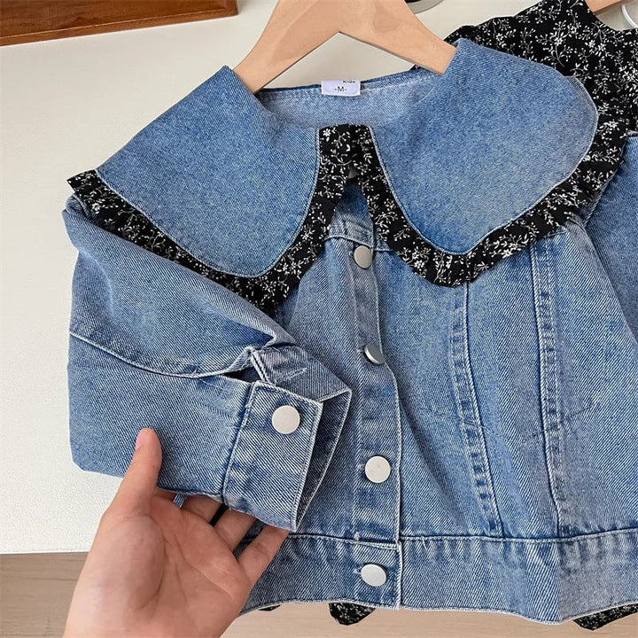 Denim jacket close-up showing its rounded collar, floral ruffle trim, and silver-tone fastenings