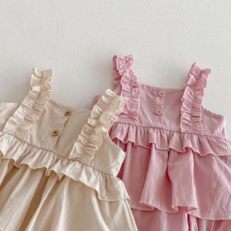 Buttoned bodices and ruffled shoulder straps on apricot and pink baby dress rompers