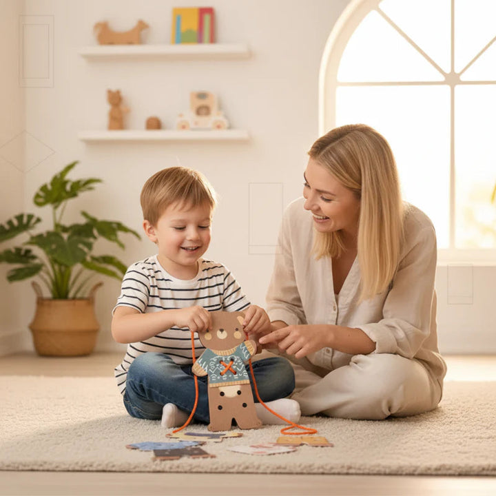 An adult and child lace the wooden bear together on a rug with clothing pieces nearby.