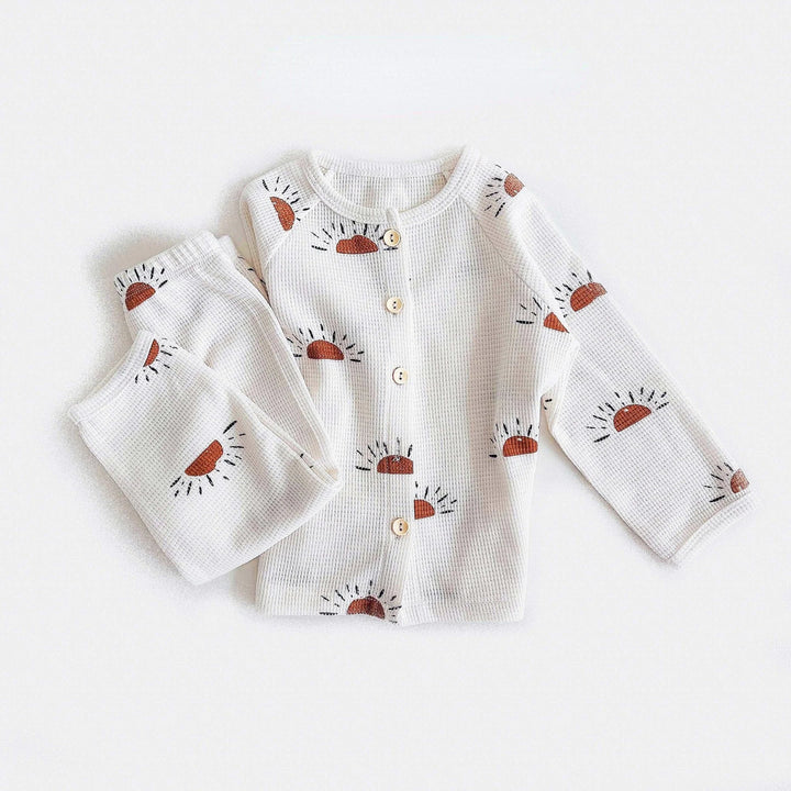 White cotton pajama set with rust-colored sun prints and a button-front top
