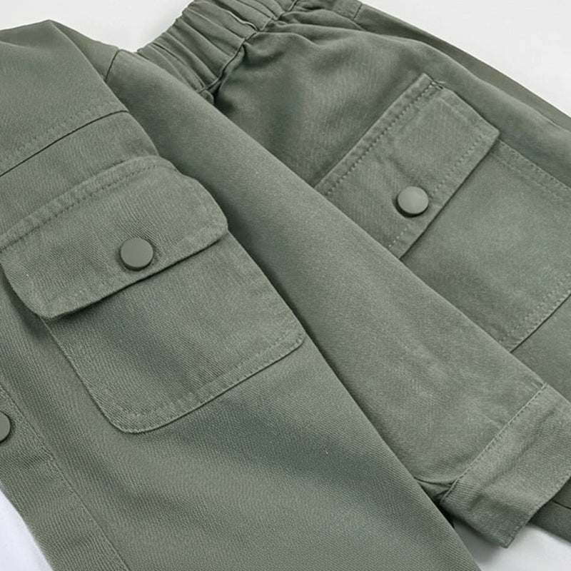 Close-up of sage green flap pockets, stitching and an elastic waistband