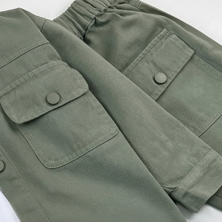 Close-up of sage green flap pockets, stitching and an elastic waistband
