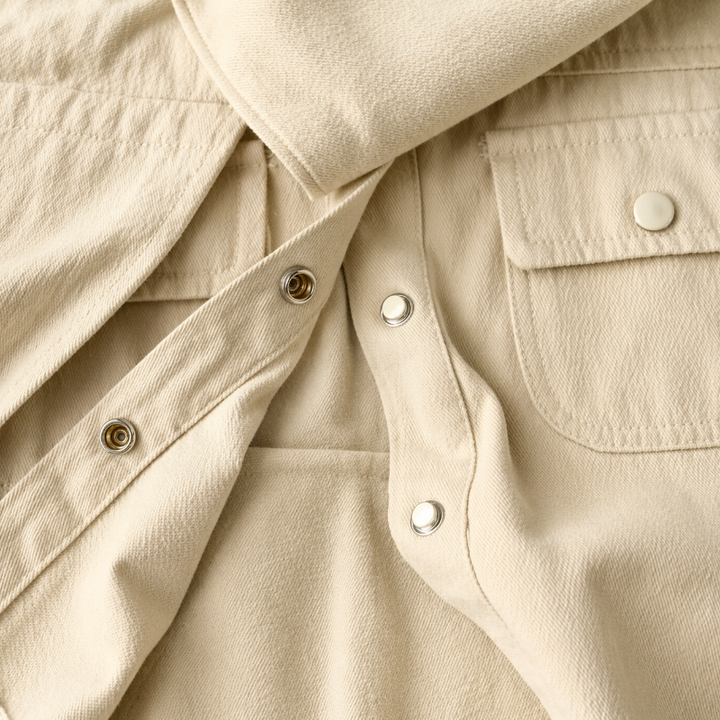 Close-up of sand beige cotton twill, shirt snap fasteners and a flap chest pocket