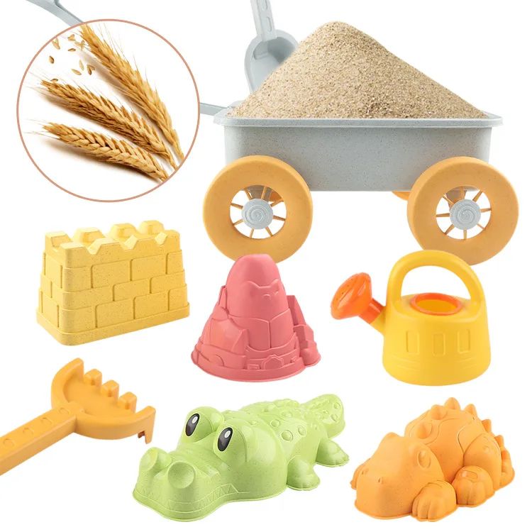 Wagon filled with sand beside castle and animal molds, a rake, and a watering can