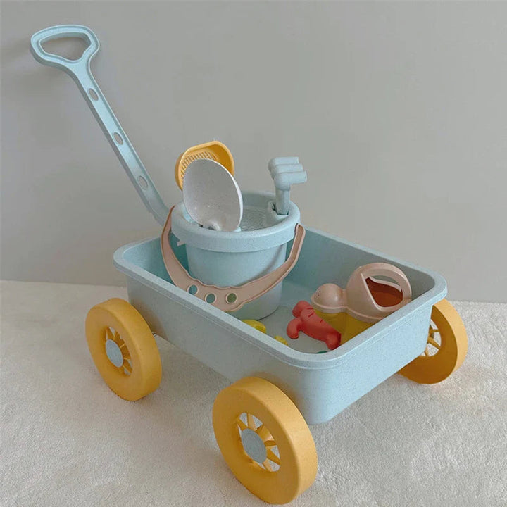 Blue pull-along beach wagon with yellow wheels, a bucket, watering can, and sand tools