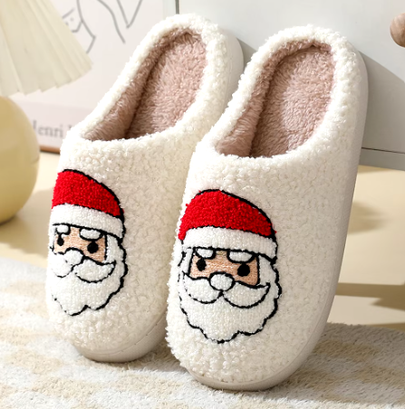 Cream plush slippers decorated with Santa faces and red hats.