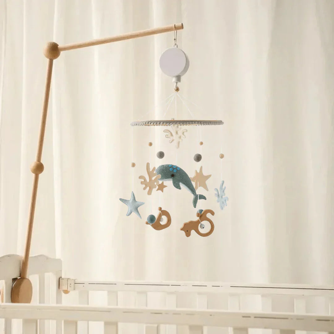 Seabed baby mobile with sea creatures and coral shapes displayed on a wooden arm beside a crib