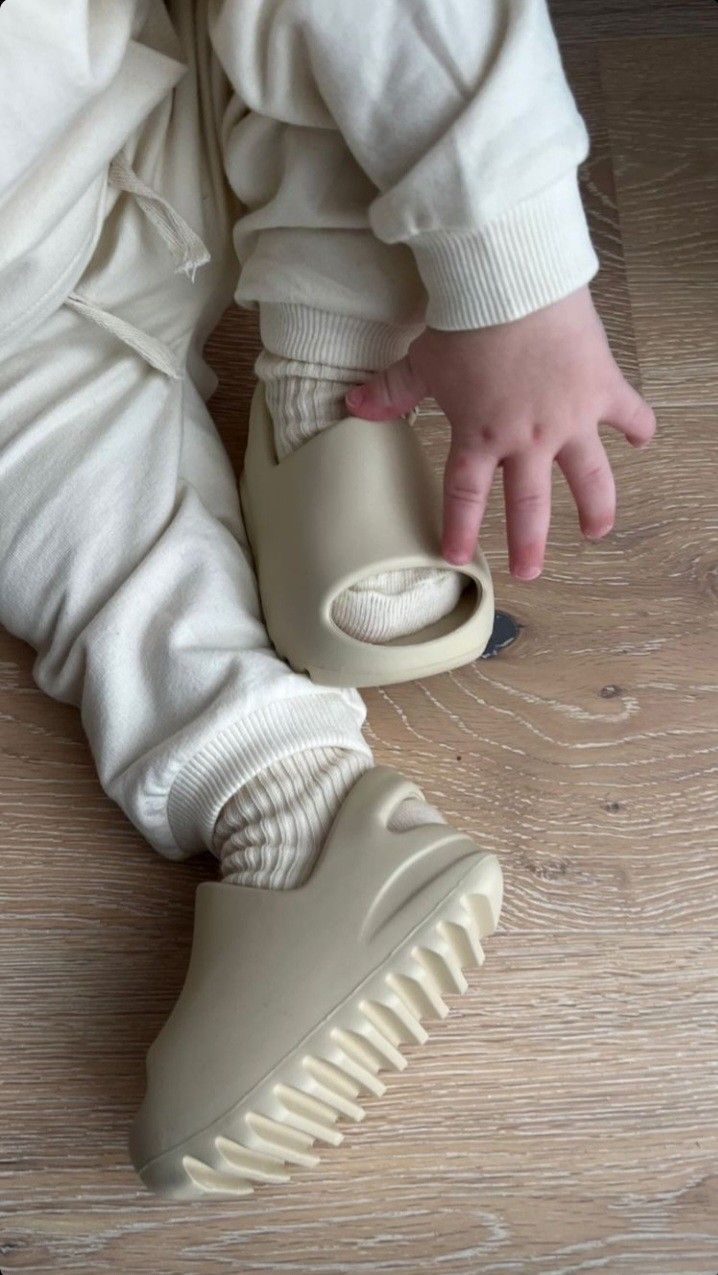 Seated child wearing beige sandals, with the ridged sole visible on one foot.