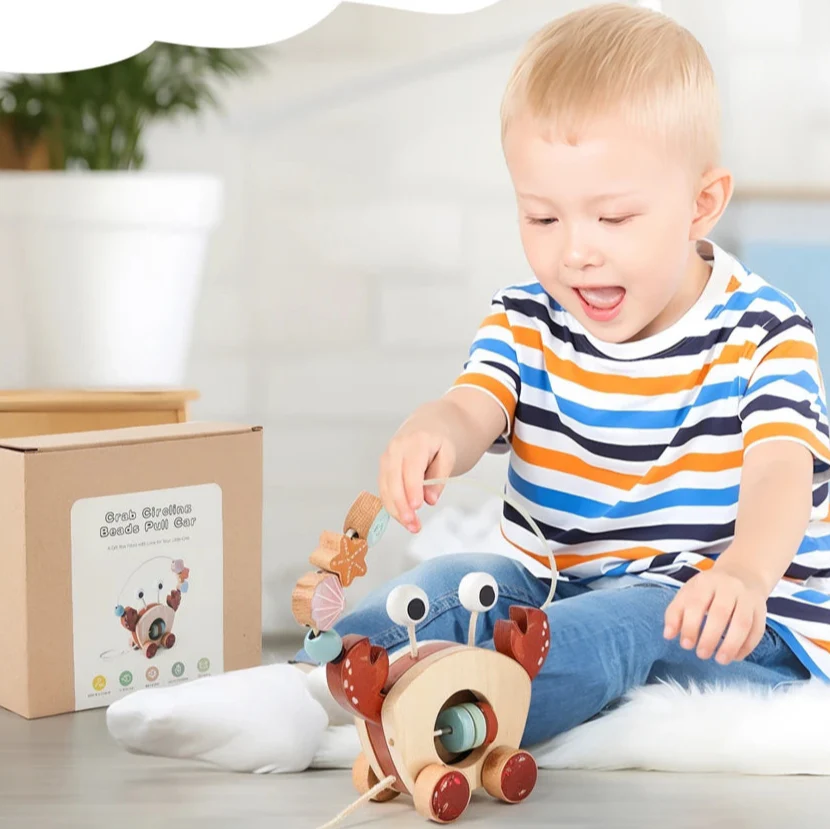 Seated child reaching for the beads on a wooden crab pull toy