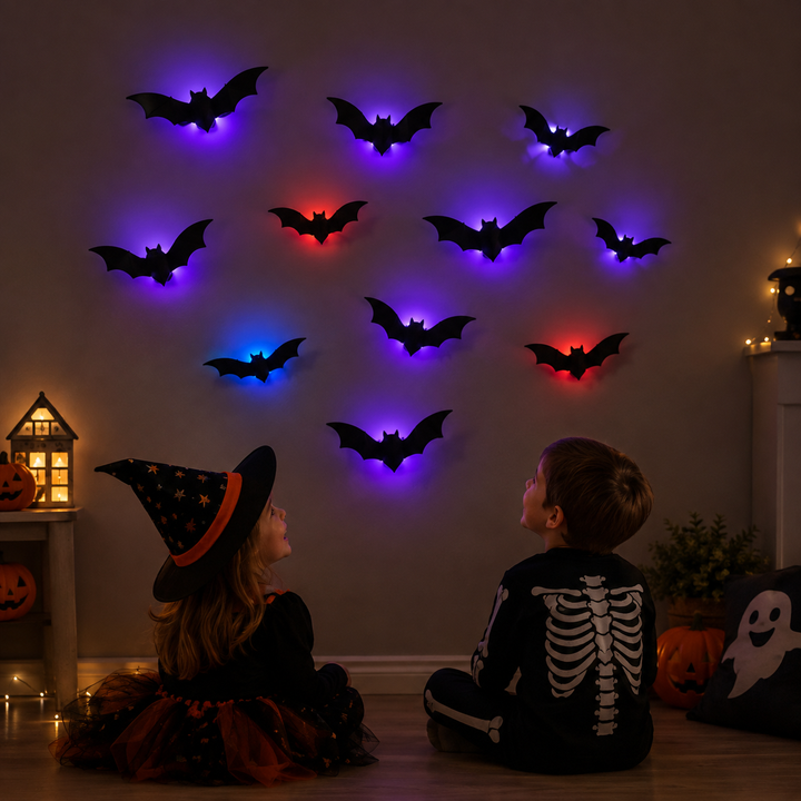 Two children seated beneath a Halloween bat display with colorful LED lighting