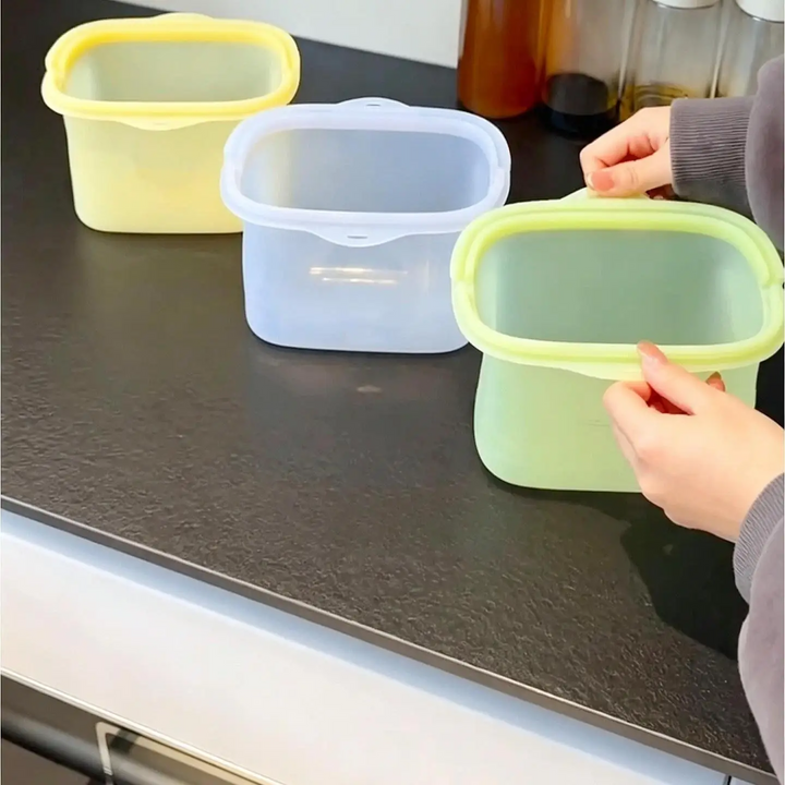Three open silicone food storage bags standing upright on a kitchen counter.
