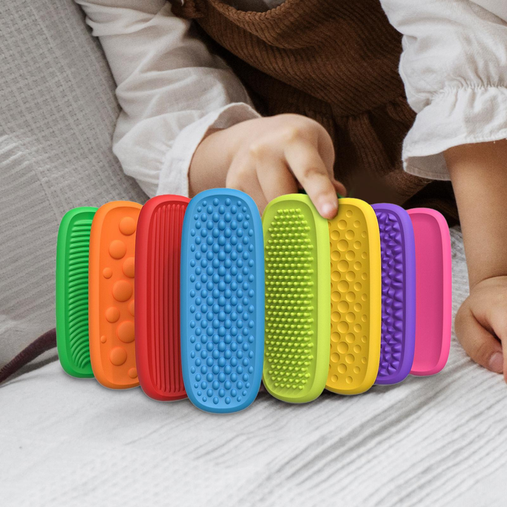 Child touching a row of upright, colorful textured silicone strips on a sofa.