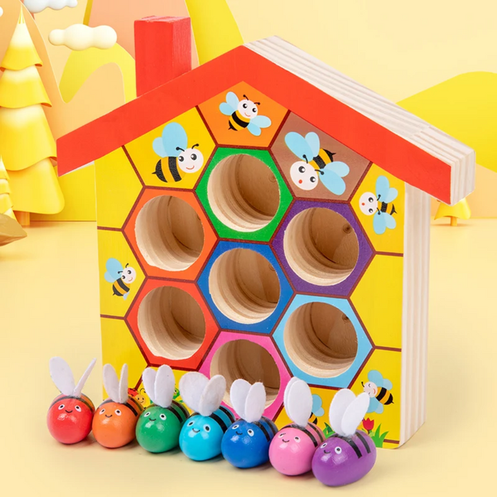 Seven colorful bees lined up beneath a wooden hive with matching colored openings