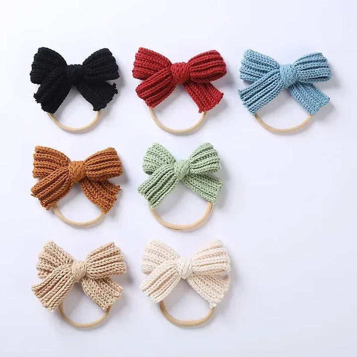 Seven knitted bow headbands arranged in rows, including black, red, blue, and green