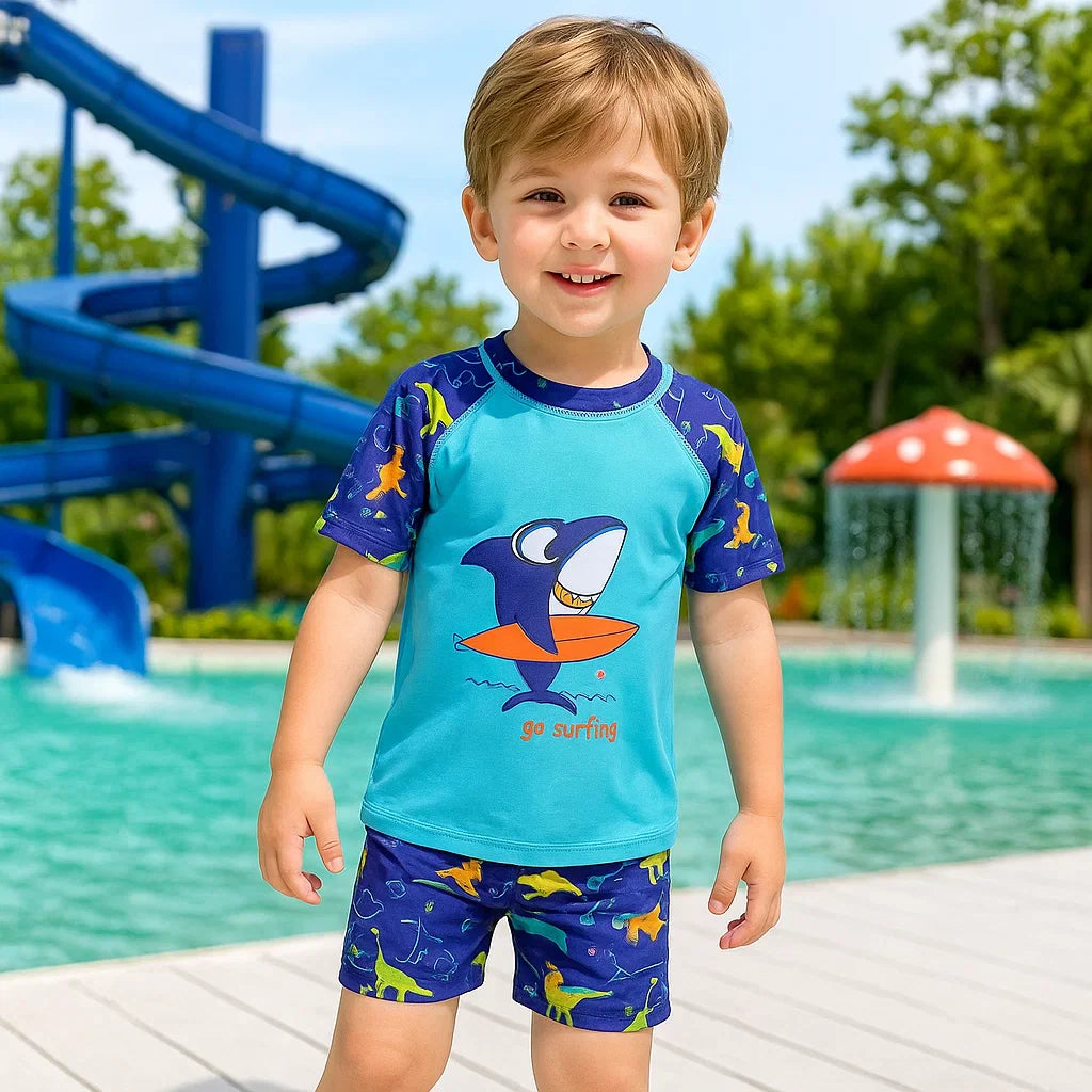 Child wearing a blue shark swim shirt and patterned shorts at a water park