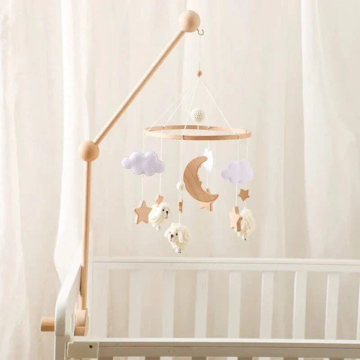 Sheep baby mobile with a crescent moon and clouds displayed on a wooden arm in a nursery