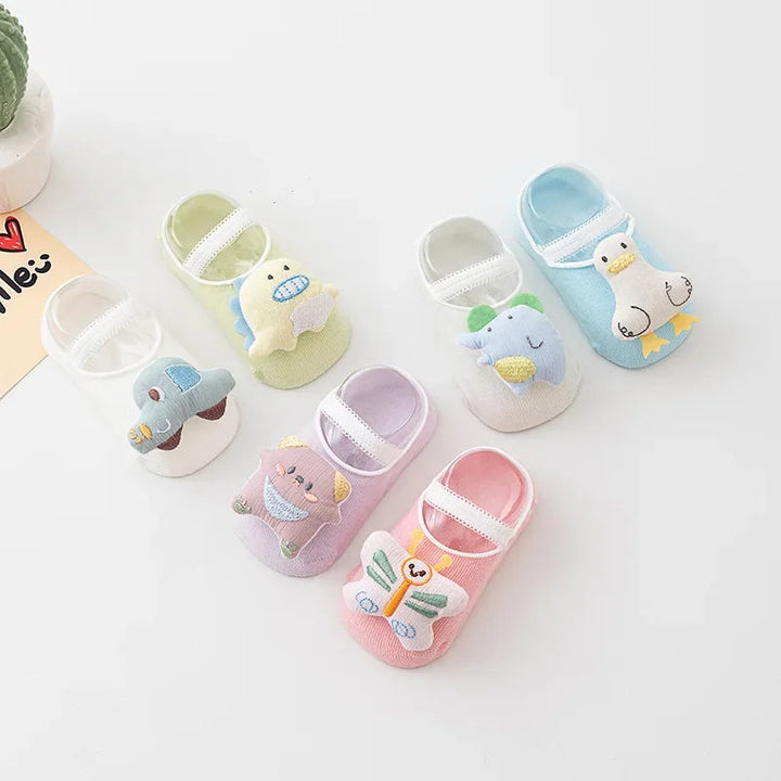 Six pastel baby sock styles with raised character decorations arranged on a white surface