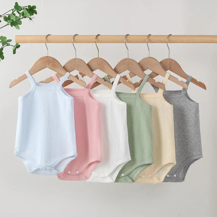 Blue, pink, white, green, yellow, and gray baby bodysuits hanging side by side
