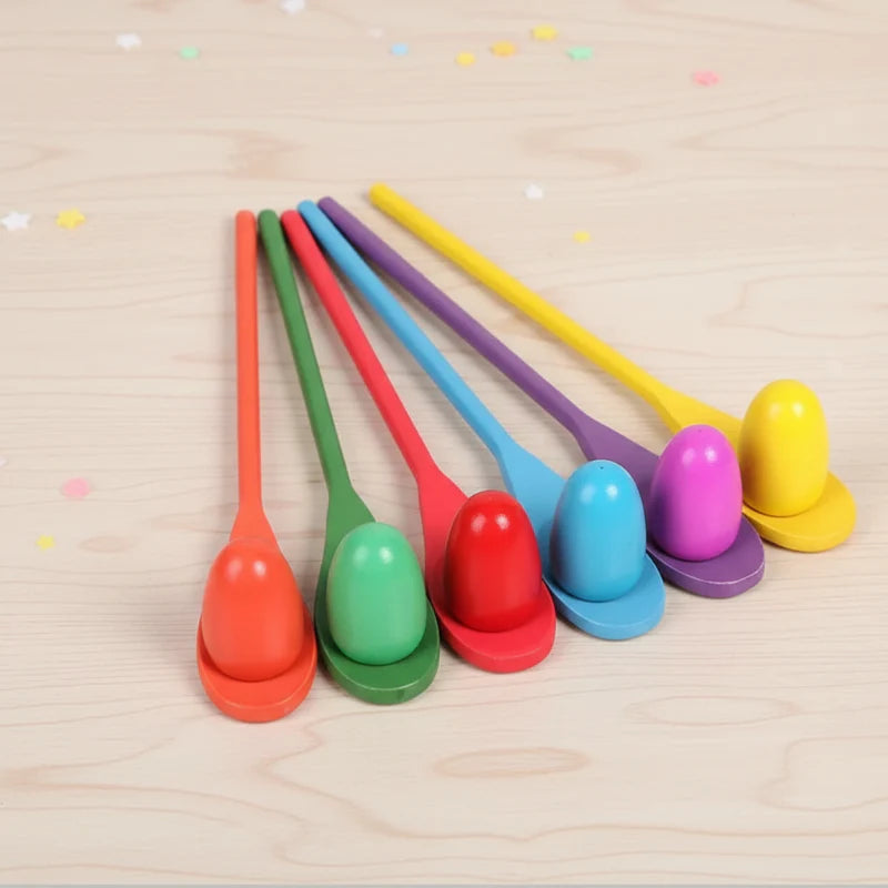 Six wooden spoons and colorful eggs arranged on a light wood surface.
