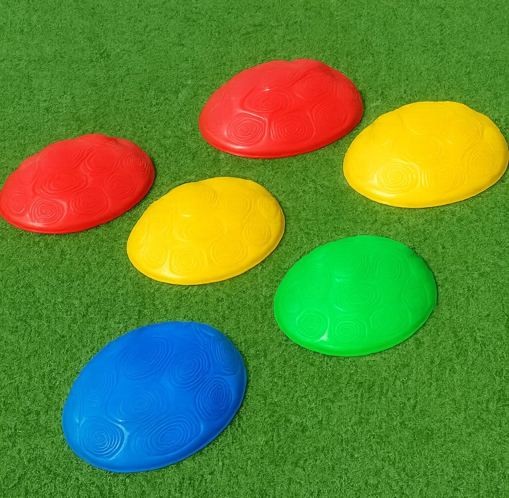 Six red, yellow, green, and blue balance stepping stones arranged on grass