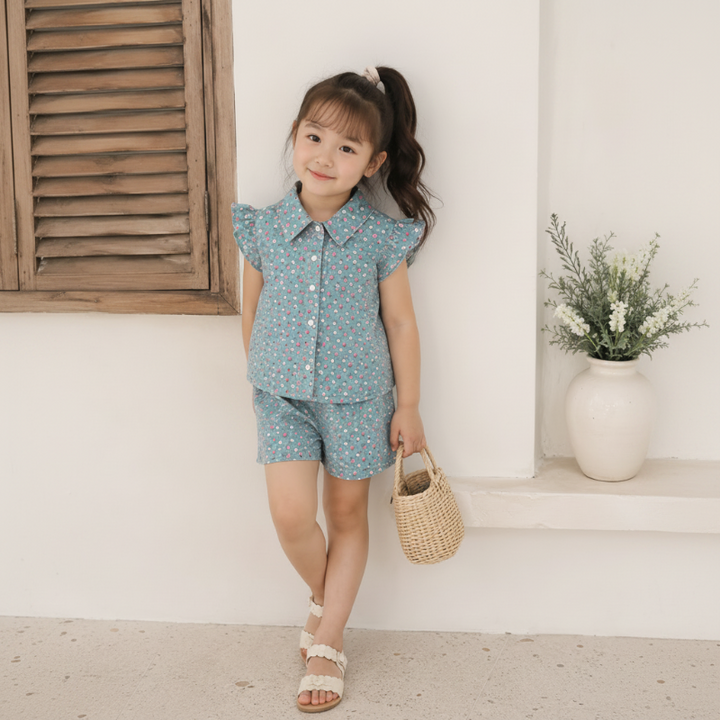 Child wearing a blue small-floral collared top and matching shorts