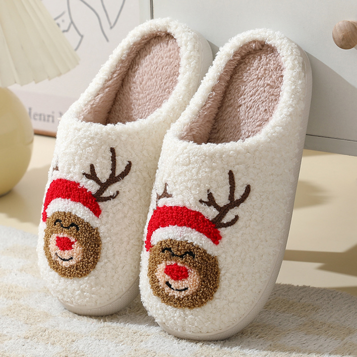 Cream plush slippers with smiling reindeer faces, antlers and red Santa hats.
