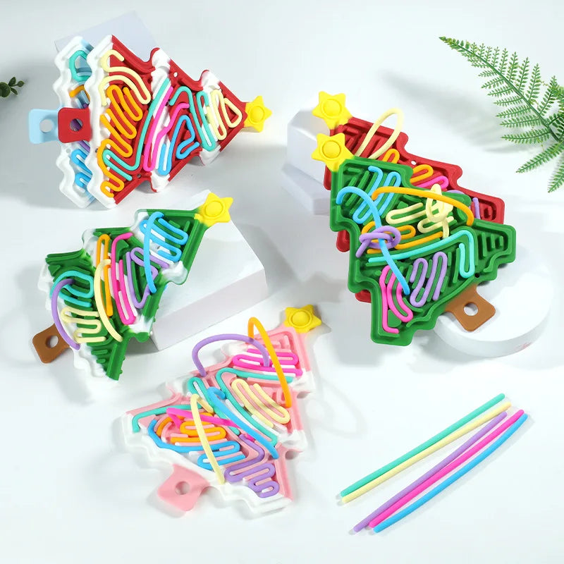 Snow-accented and plain Christmas tree fidgets beside loose colorful cords