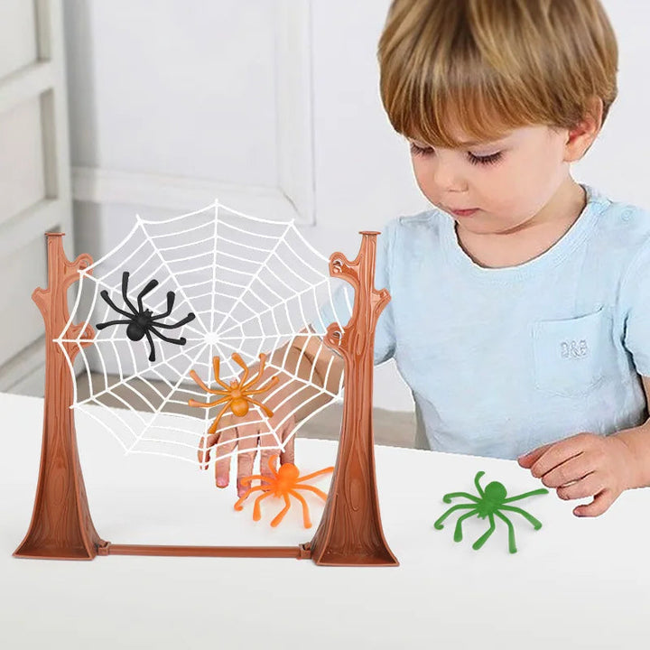 Child playing with colorful spiders on a white web held between brown tree-shaped posts