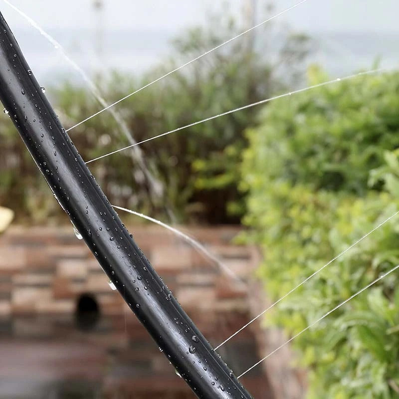 Close-up of thin streams of water spraying from a black trampoline sprinkler hose.
