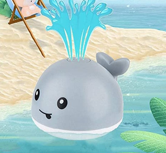 Gray whale bath toy spraying water against an illustrated beach background.