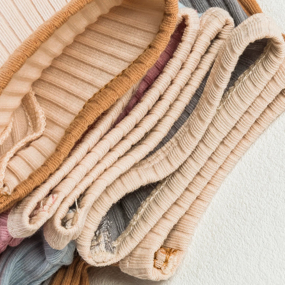 Stacked ribbed cotton baby rompers showing contrasting bound edges