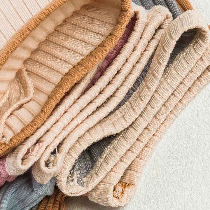 Stacked ribbed cotton baby rompers showing contrasting bound edges
