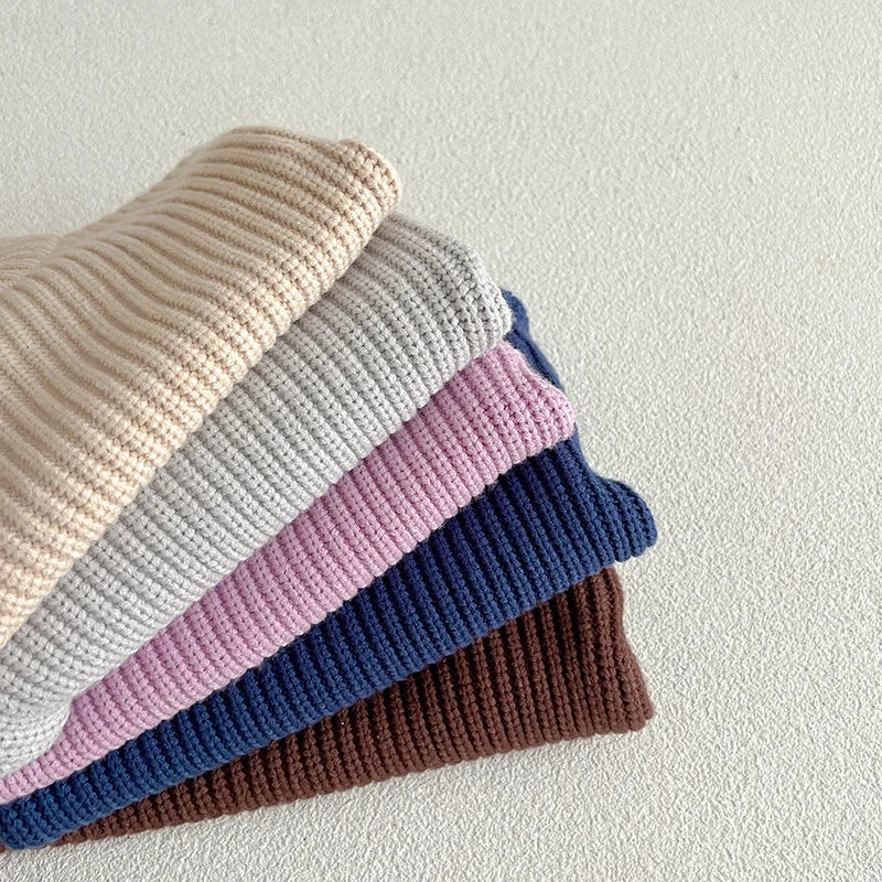 Stacked sweaters showing cotton knit texture in apricot, gray, purple, dark blue, and brown.