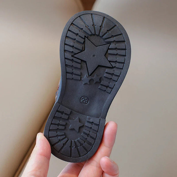 Black rubber boot sole with star shapes and a grooved tread pattern